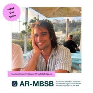 Francisco sitzt an einem Tisch im Außenbereich eines Cafés. Er hat lange, dunkle Haare und lächelt in die Kamera, während er seinen Kopf mit einer Hand abstützt. Im Hintergrund sind weitere Sitzplätze und Menschen zu sehen.